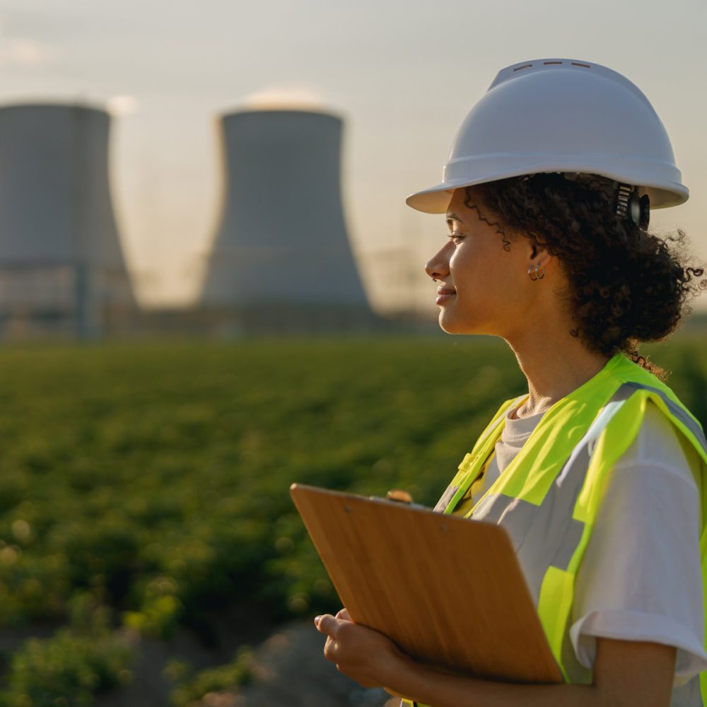 Female engineer constructor stands with clipboard on field on industrial enterprise background Smiling female engineer constructor stands with clipboard on industrial enterprise background